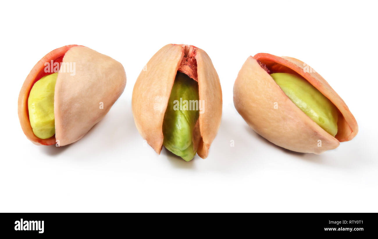 Three red turkish pistachios, peeled green nuts visible in cracked