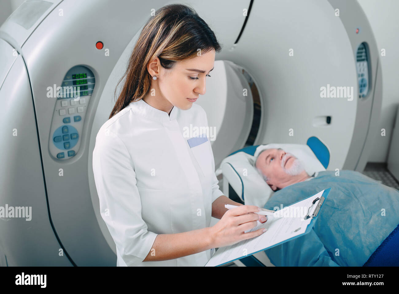 doctor write into medical chart after CT Scan in hospital.CT Scan senior patient Stock Photo