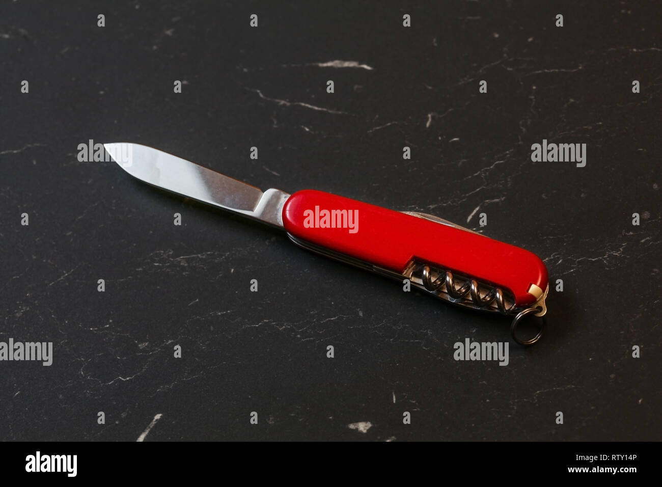 Red pocket knife on black table. Stock Photo
