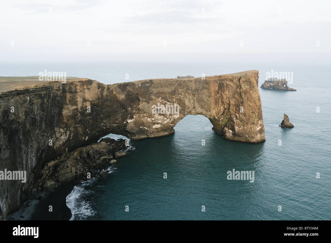 Peninsula Dyrholaey, southern coast of Iceland. Muffled landscape in discreet colors conveying loneliness and state of mind. Rock arch on the ocean. B Stock Photo