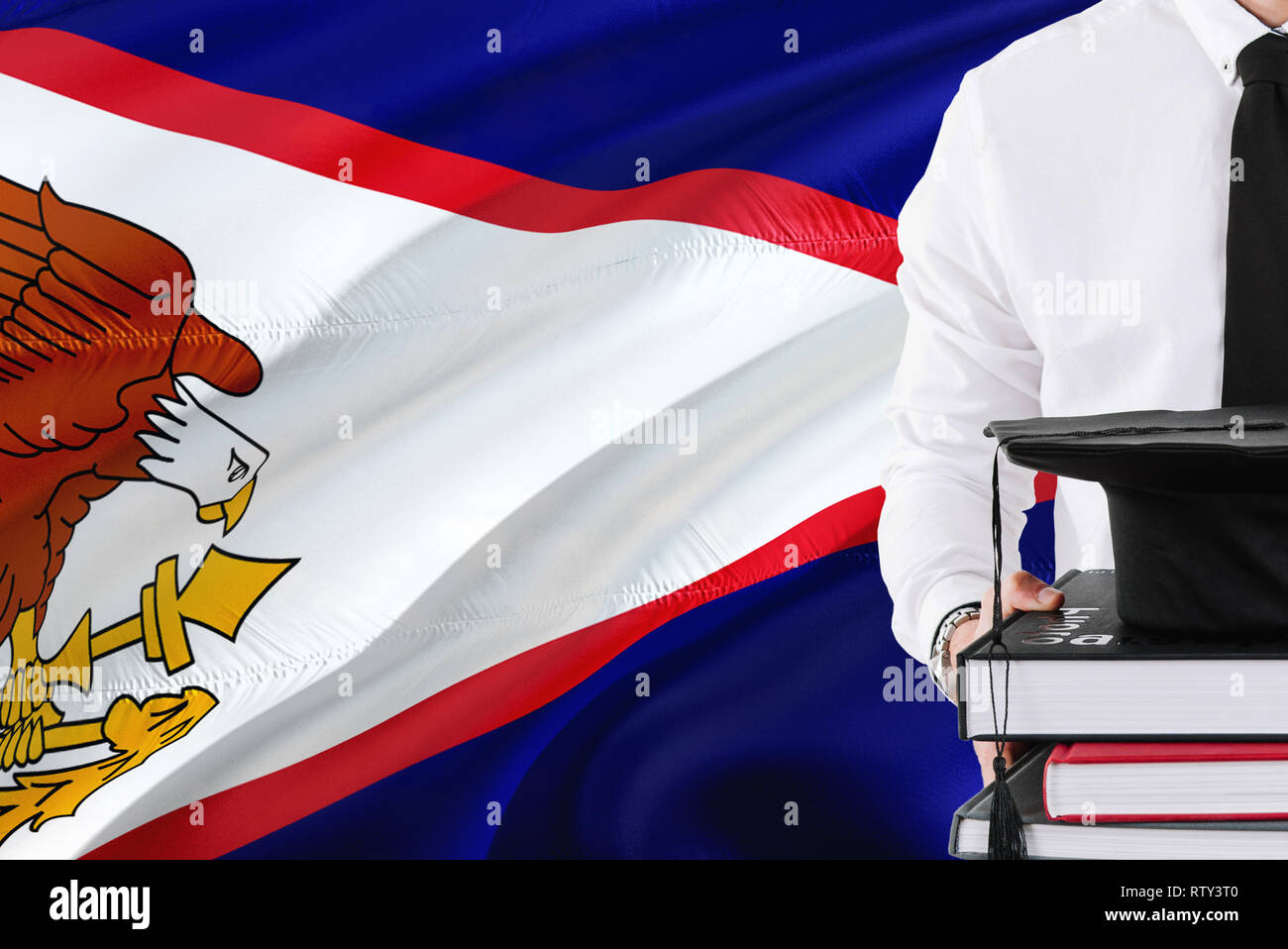 Successful student education concept. Holding books and graduation cap over American Samoa flag background. Stock Photo
