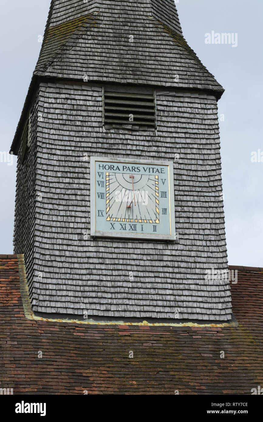 Sundial on the shingled spire of St Michael and All Angels Church in Thursley, Surrey, UK, with the latin phrase Hora Pars Vitae Stock Photo
