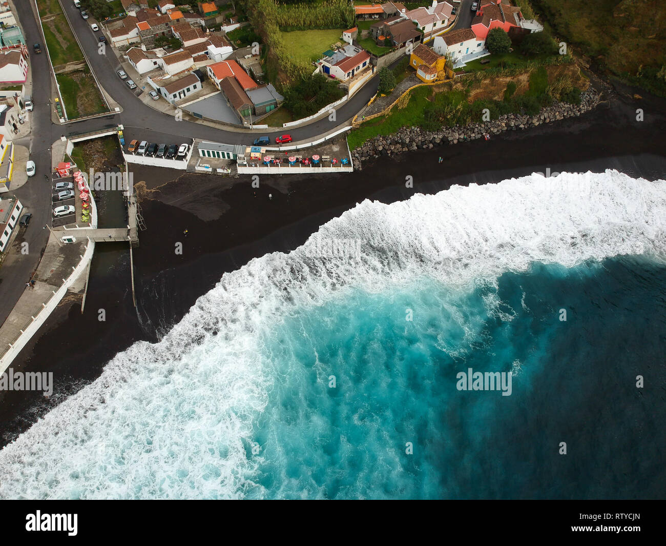 Aerial top view of sea waves hitting a beach with black volcanic sand ...