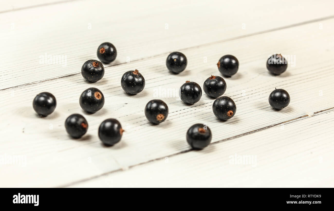 Blackcurrants (Ribes nigrum) spilled on white boards desk Stock Photo