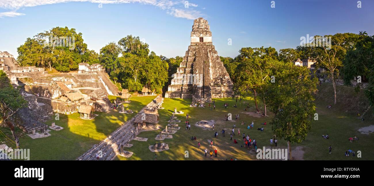Panoramic Aerial View of Tourists and Grand Plaza Landscape surrounded by Ancient Mayan Citadels and Temple Ruins in Tikal National Park, Guatemala Stock Photo