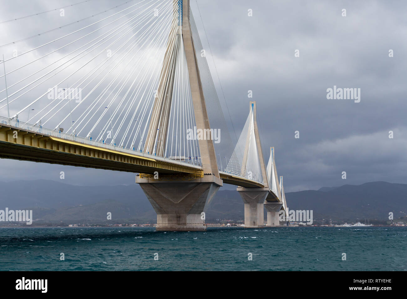 View at the gulf of Corinth and Rio–Antirrio bridge from below from the  Pio town on the Peloponnese peninsula side on a cloudy spring day. Greece Stock Photo