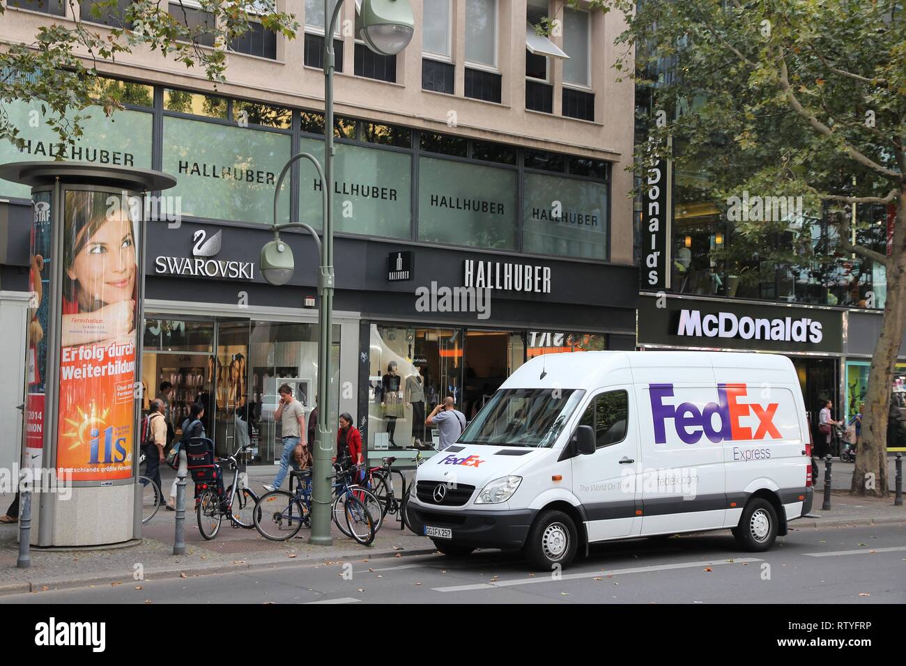 BERLIN, GERMANY - AUGUST 27, 2014: People walk by Fedex Express courier van in Berlin. Fedex is one of largest package delivery companies worldwide wi Stock Photo