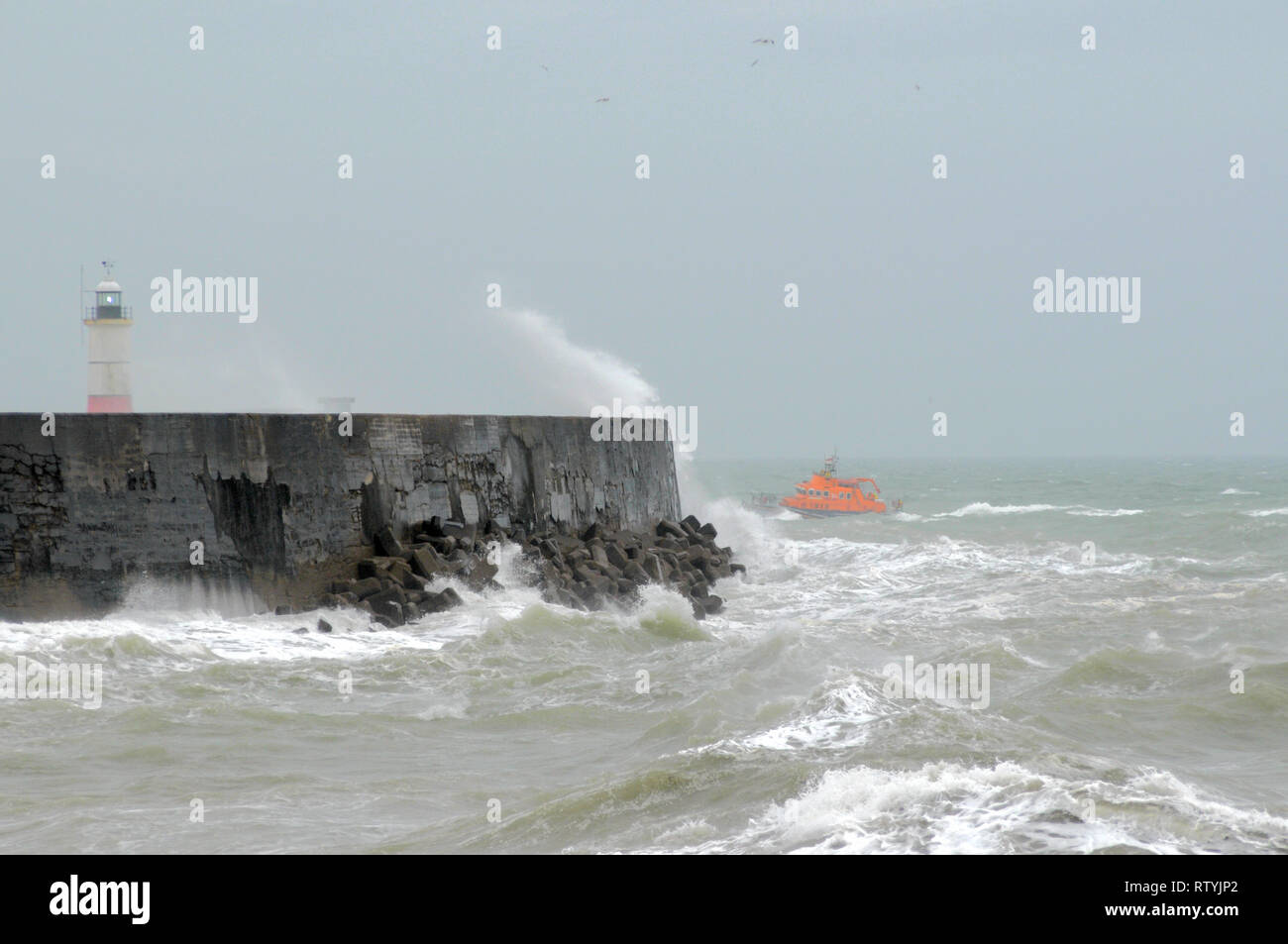 Newhaven, East Sussex, UK..3 March 2019.. Increasing wind from storm Freya whipping up the waves along the Sussex Coast .Lifeboat returns to harbour. Stock Photo