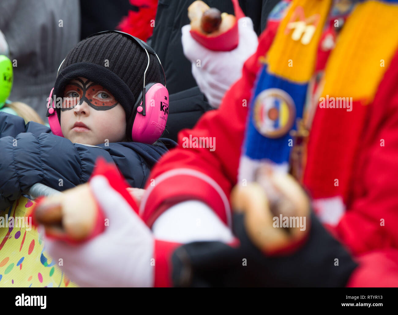03 March 2019, Hessen, Frankfurt/Main: A little boy with a face painting and hearing protection stands on the grandstand during the carnival procession on the Römerberg. According to the Grand Council of Frankfurt Carnival Associations, about 300,000 to 400,000 spectators will line the train. The plan includes 92 cars and more than 3100 active people. Photo: Frank Rumpenhorst/dpa Stock Photo