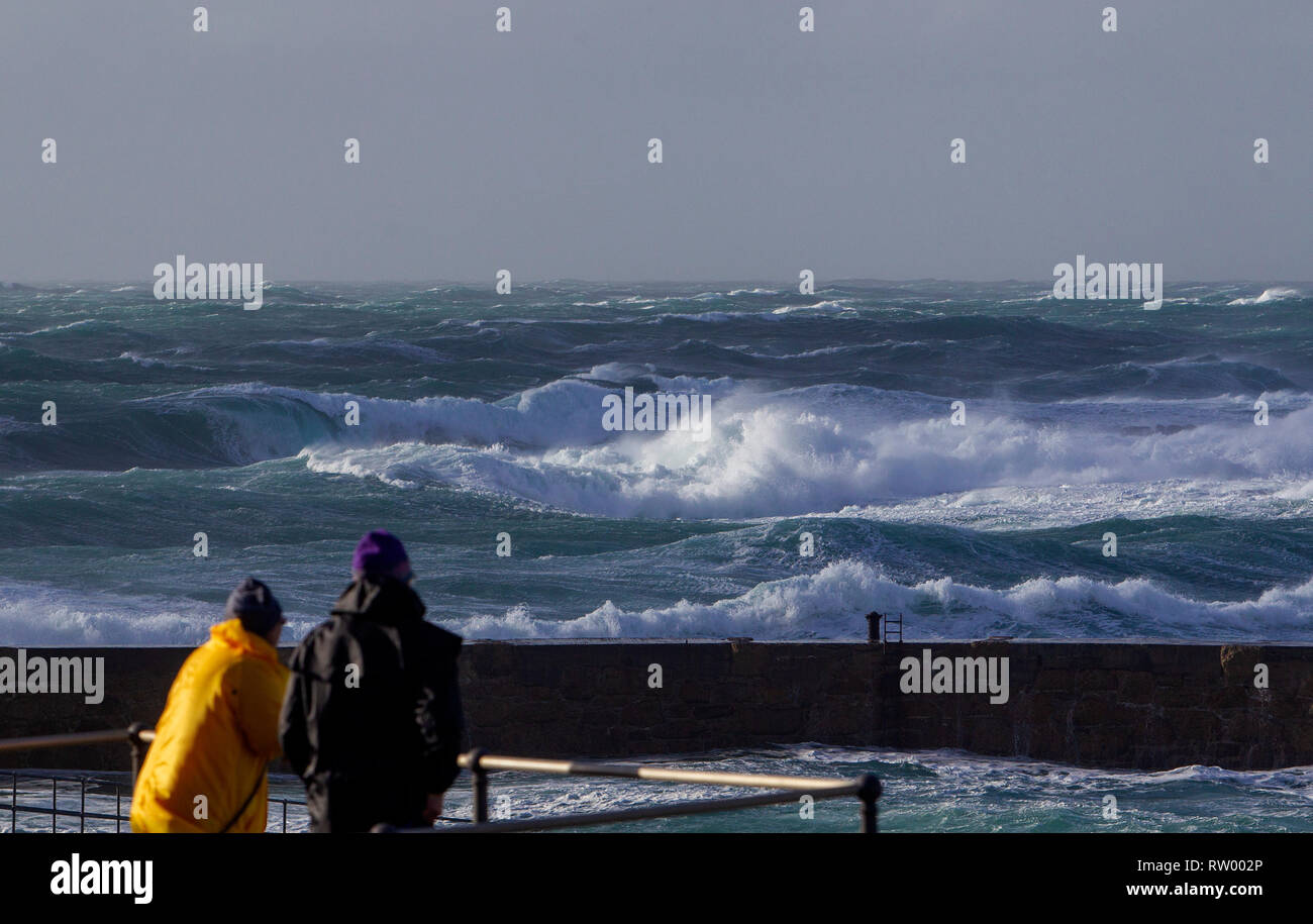 Sennen, Cornwall, UK. 3rd  March 2019. Gale force winds and 20ft high waves lash the granite cliffs of Cornwall. Daring jumpers get caught by some huge waves swamping the pier. Credit: Mike Newman/Alamy Live News. Stock Photo