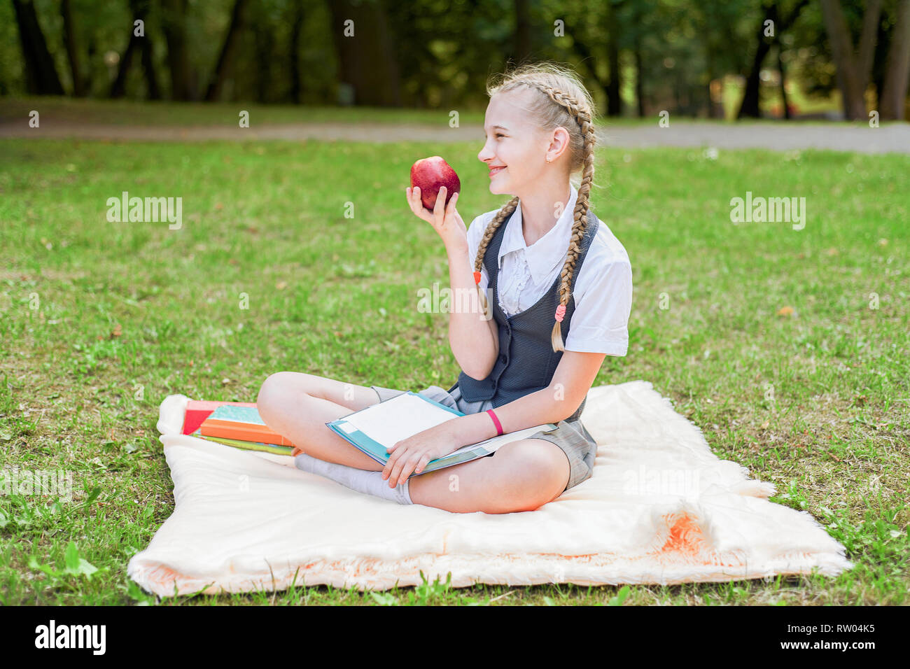 student happy smiling with apple in hand. schoolgirl sitting on a ...
