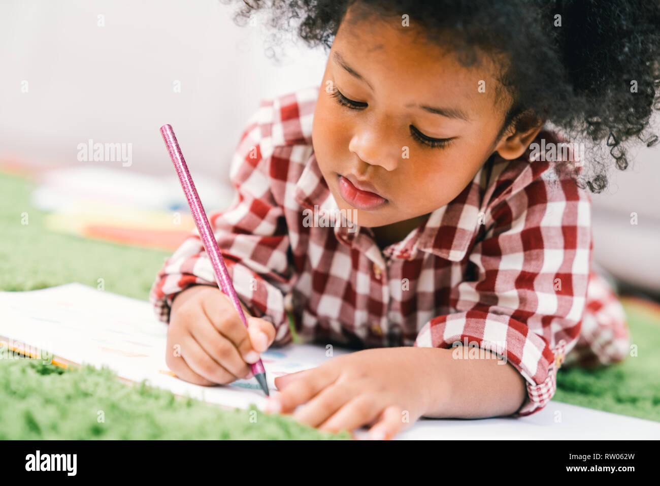 Cute young African American kid girl drawing or painting with colored pencil. Kindergarten children education, back to school, or preschool child Stock Photo