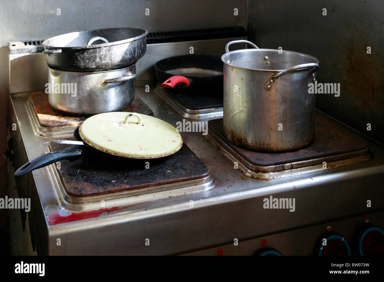 Dirty pots and pans are placed on a stainless steel electric stove on the galley on the ship Stock Photo