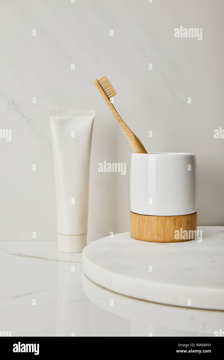 holder with bamboo toothbrush and toothpaste in tube on white marble ...