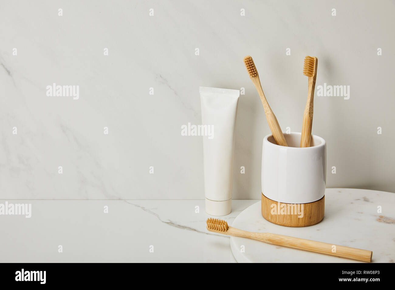 bamboo toothbrushes, holder and toothpaste in tube on white marble ...