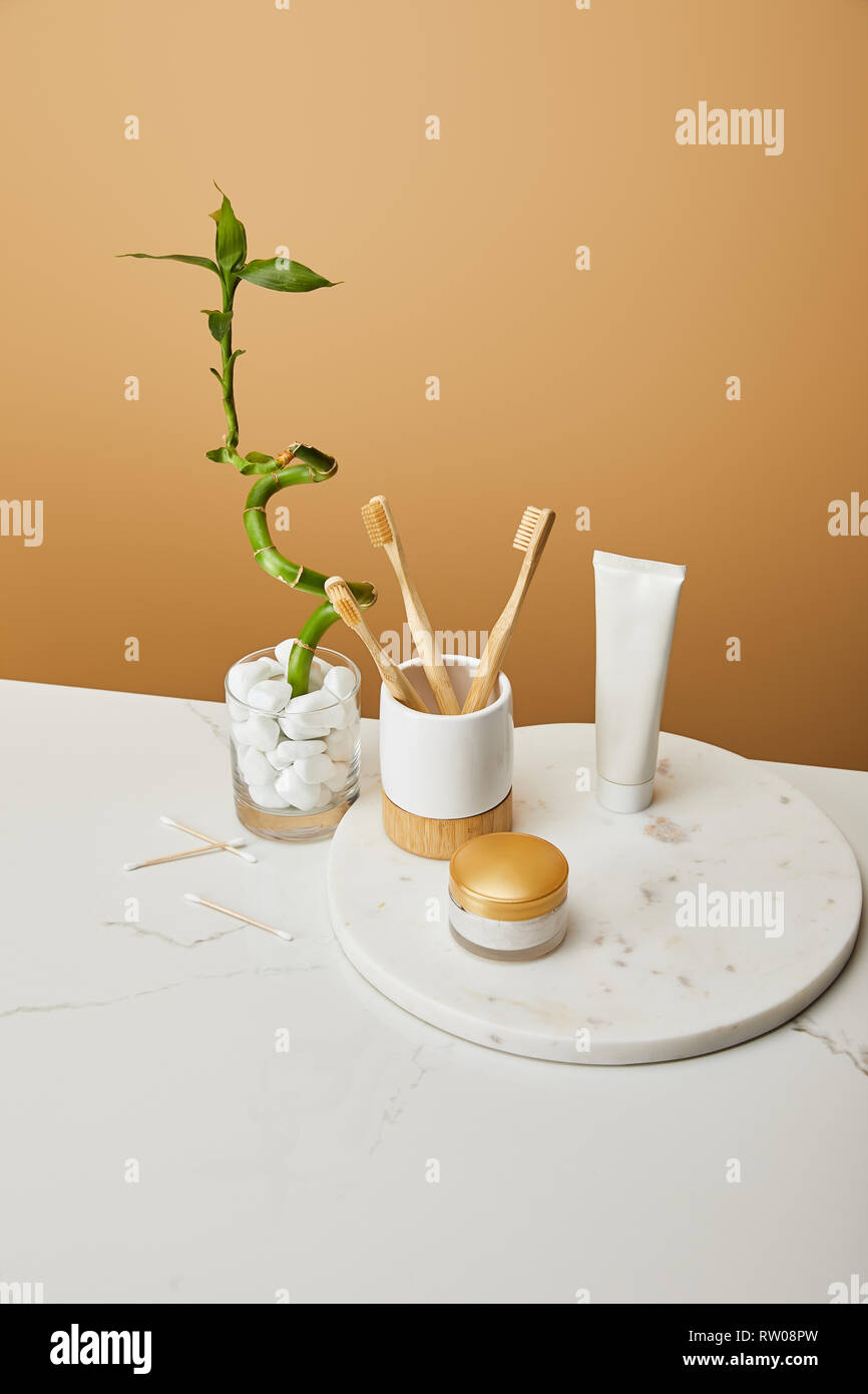 bamboo toothbrushes in holder, cosmetic cream and toothpaste in tube on ...
