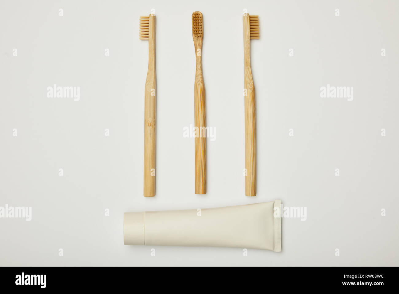 top view of toothpaste in tube and bamboo toothbrushes on white ...