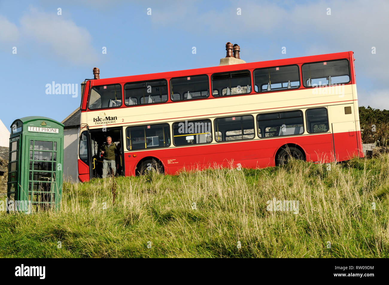 A couple of passengers alight from a local bus next to a green telephone box in a Cregneash , a hamlet on the southwest coast of the Isle of Man, Brit Stock Photo