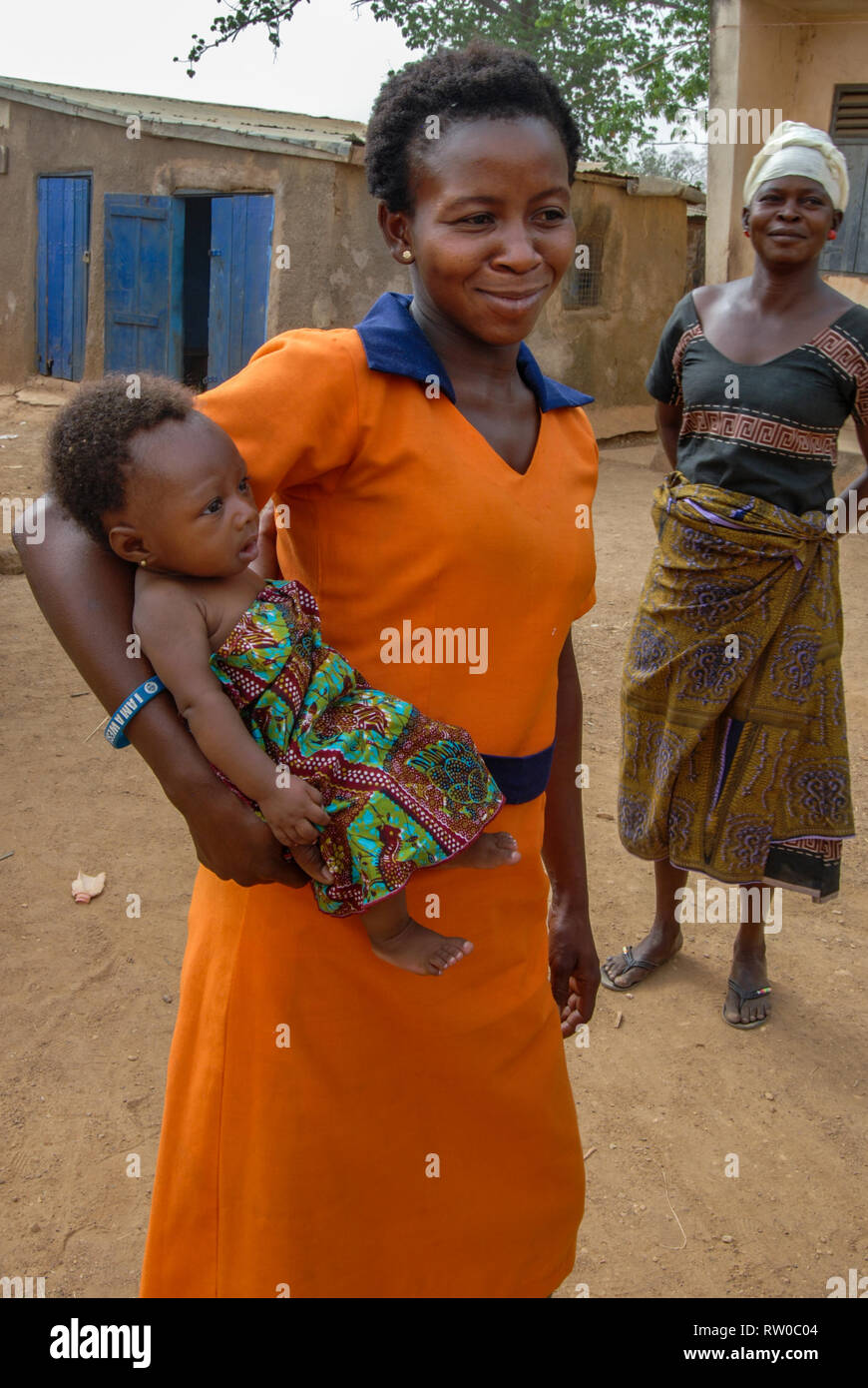 A photo of a young Ghanaian woman posing with her young baby boy dressed in a traditional Ghanaian fabric. Stock Photo