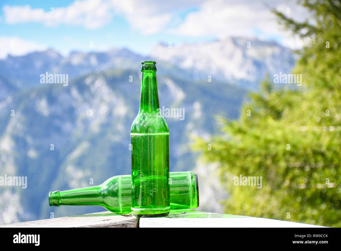 Empty green bottles of beer on a wooden fence high in the mountains background Stock Photo