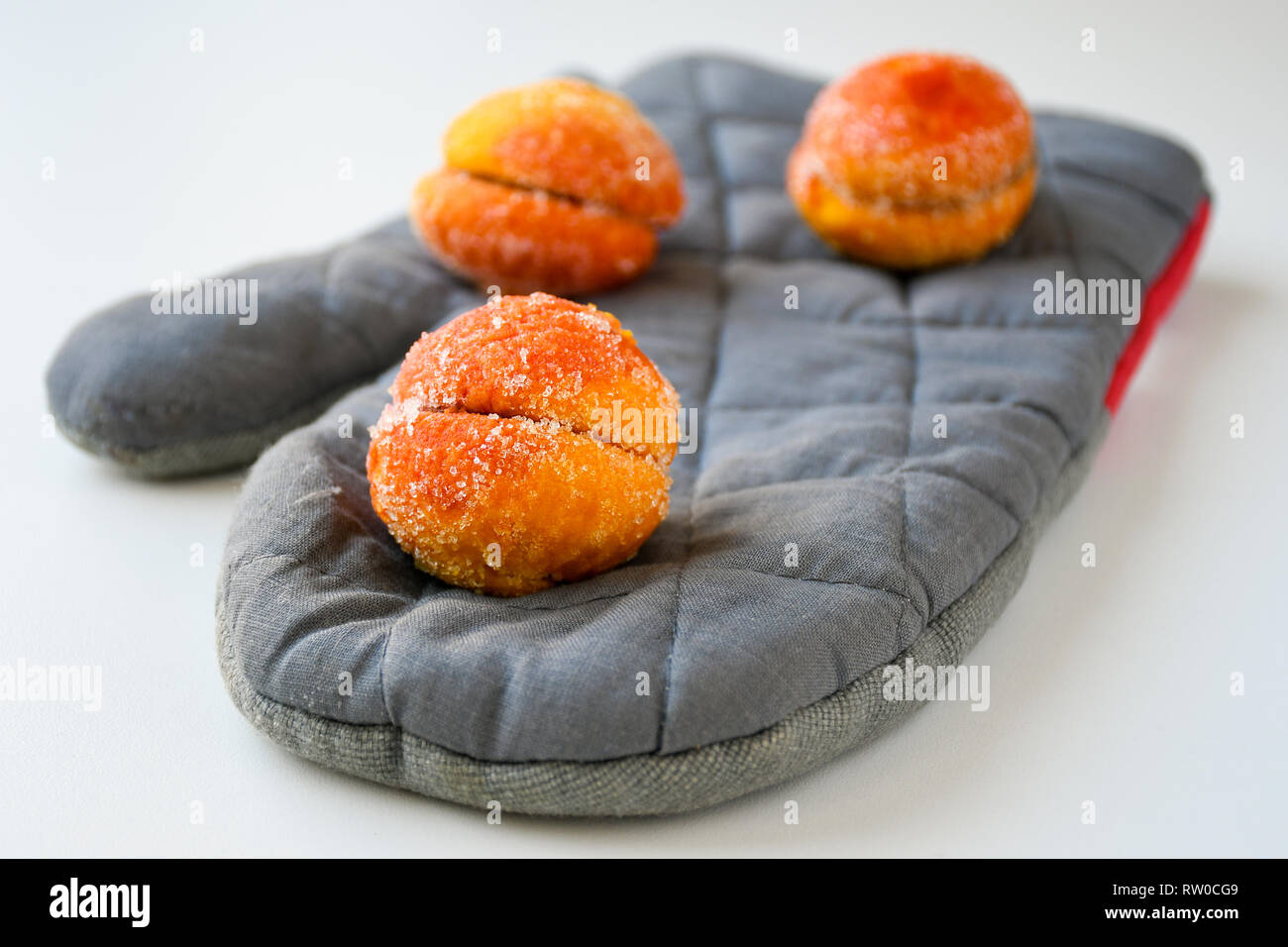 Freshly made sweet apricots with sugar coating sitting on a grey baking glove Stock Photo
