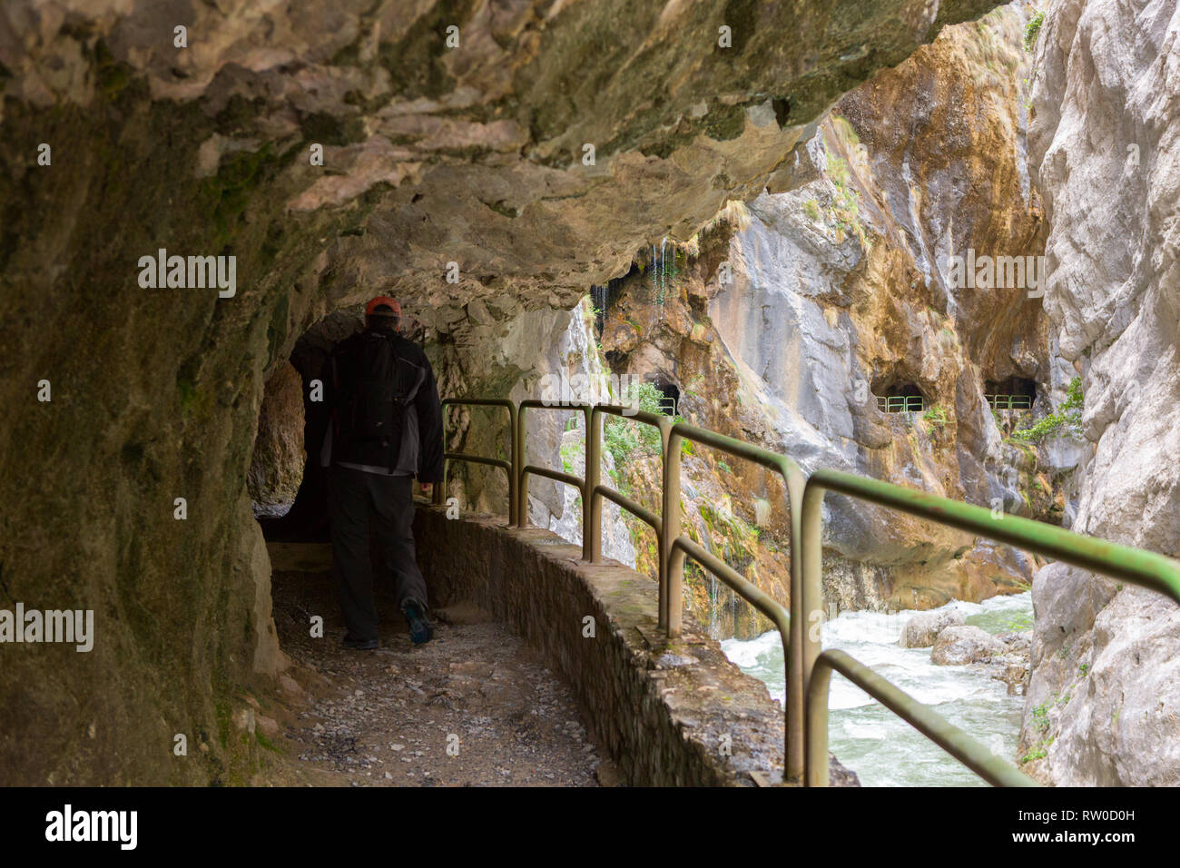 Hiking trail (Cares Trail or Ruta del Cares) in the narrow tunnel along river Cares in cloudy spring day ( near  Cain), Picos de Europa National Park, Stock Photo