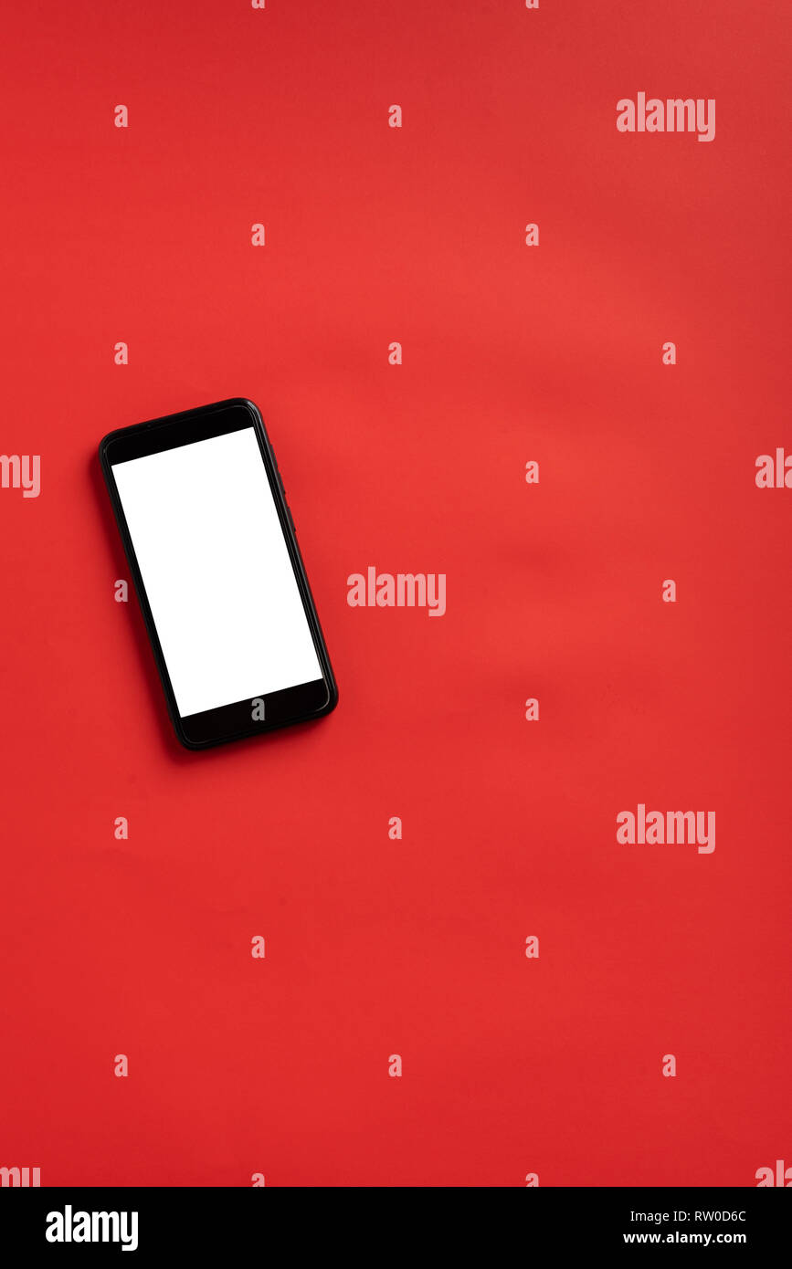 Smart phone with blank screen on red background. wireless communication concept in abstract scene. Stock Photo