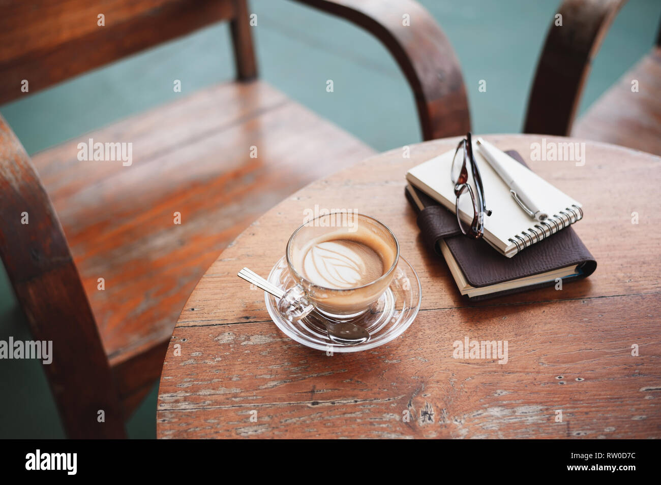 Abstract scene of coffee cup and notebooks on rustic wood table. Coffee break and relax time. Working from anywhere concept. Stock Photo