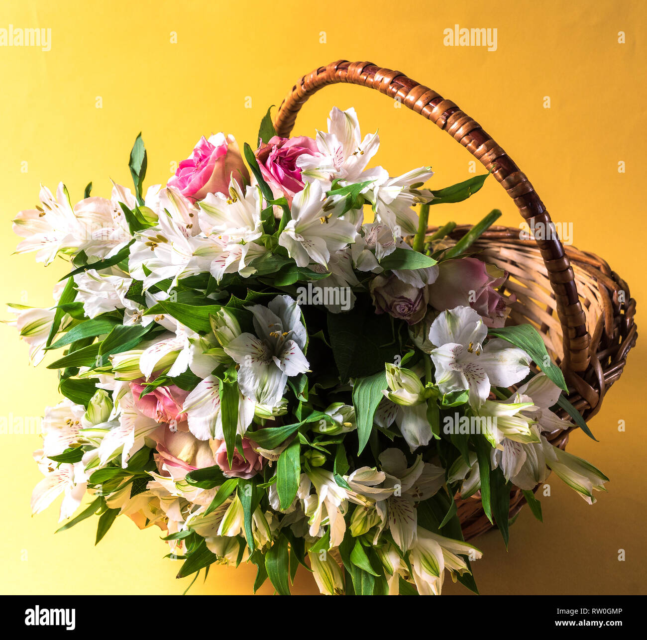 Beautiful bouquet of pink and white flowers in a basket over yellow ...