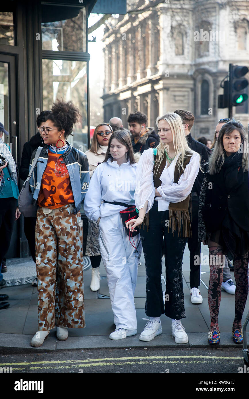 LONDON - FEBRUARY 15, 2019: Stylish attendees gathering outside 180 The Strand for London Fashion Week. Girls are waiting for a green light to cross t Stock Photo