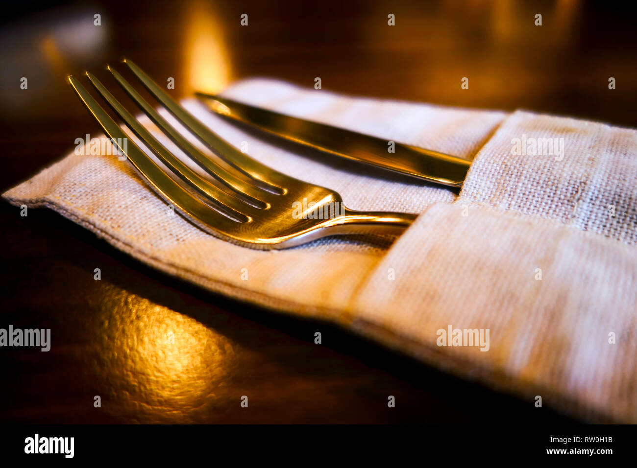 Fork and table knife in linen napkin on the table. Stock Photo