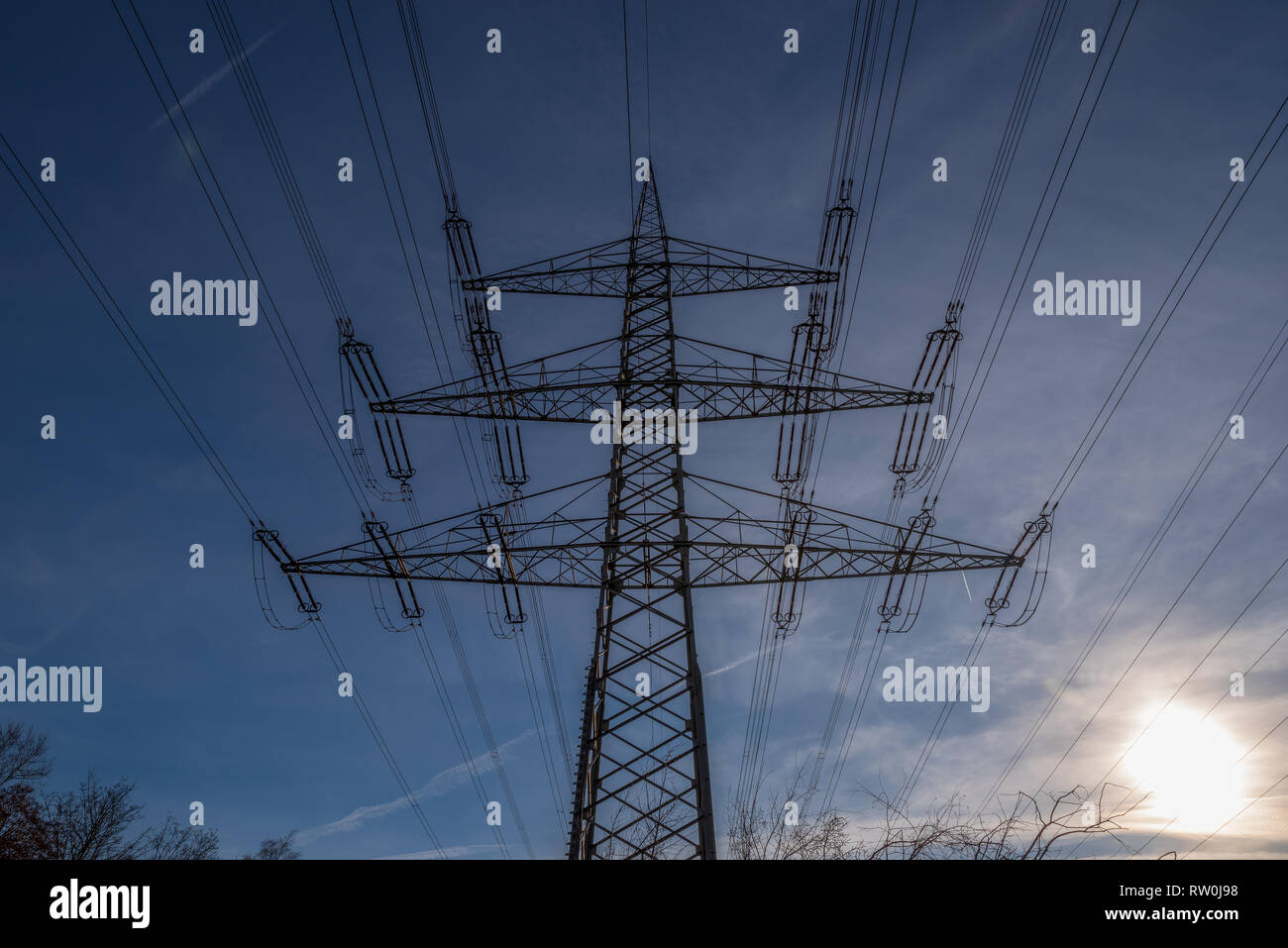 Electricity pylon against a blue sky and evening sun Stock Photo - Alamy
