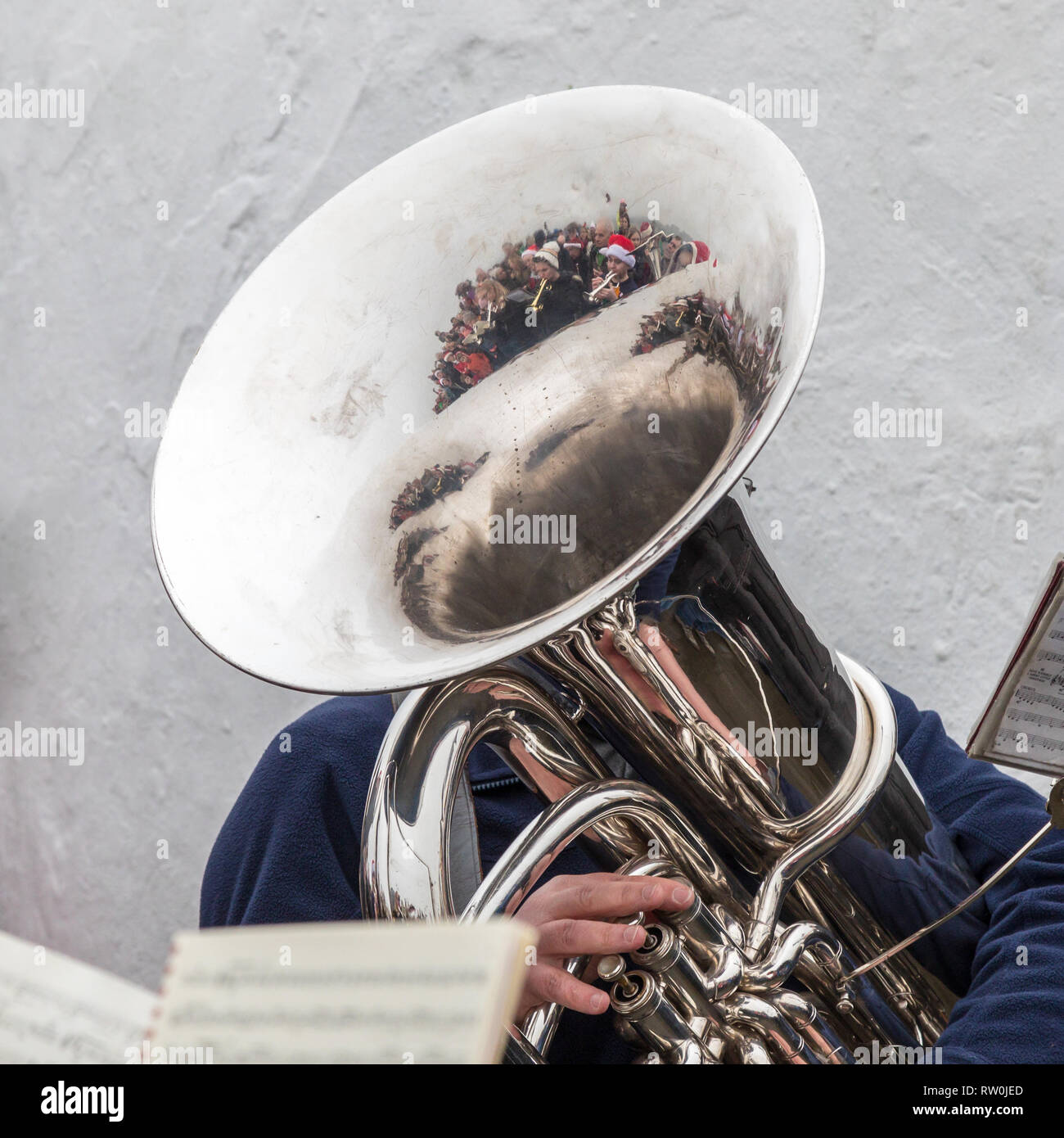 Tuba player from Bollington brass band playing carols on Christmas morning on White Nancy.  People with Christmas hats reflected in the Tuba Stock Photo
