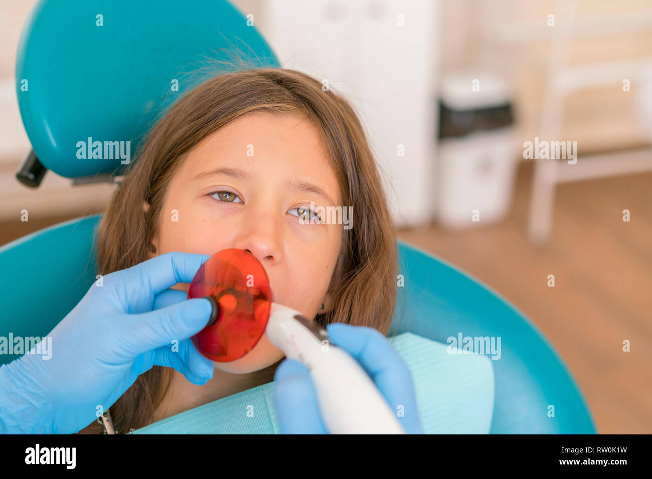 girl getting dental filling treatment at molar tooth with ultraviolet
