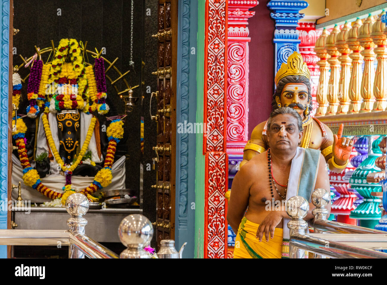 Batu Caves, Hindu Priest at Shrine in Temple at Base of Steps leading to Caves, Selangor, Malaysia. Stock Photo
