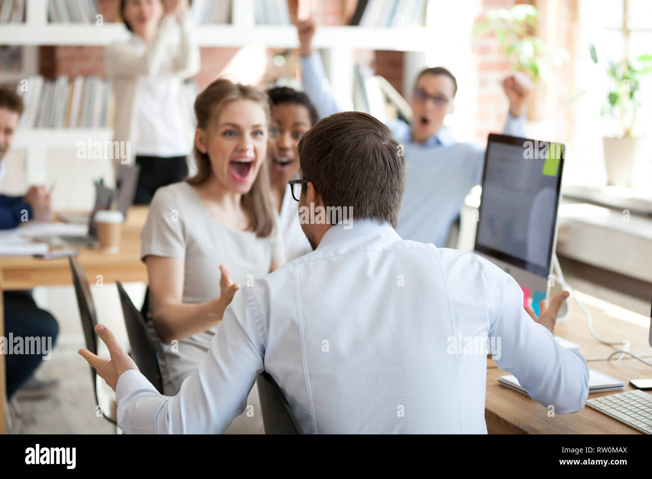 Diverse business people celebrating victory sitting in shared office ...