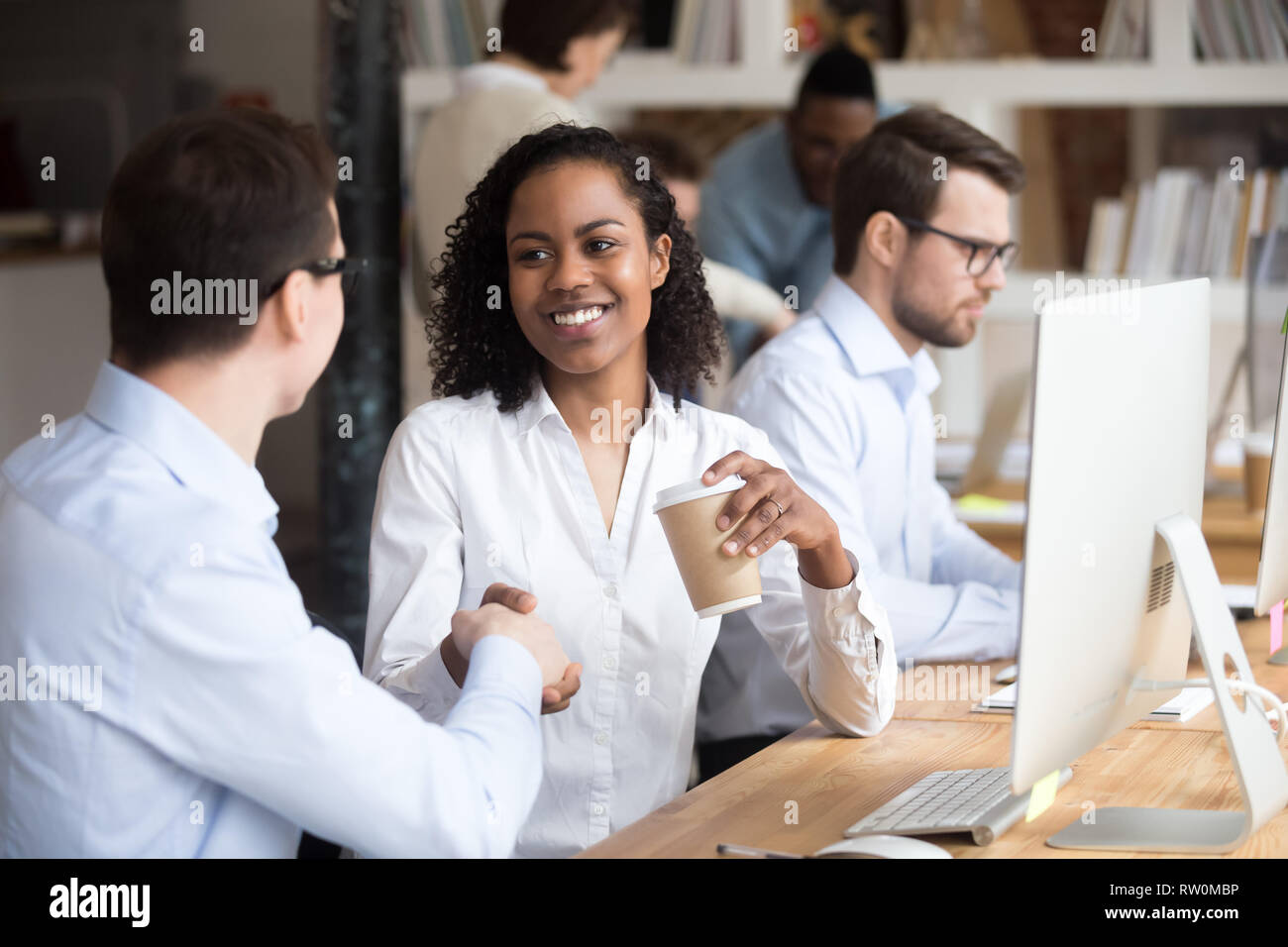 Diverse workers greeting each other shaking hands in coworking office Stock Photo