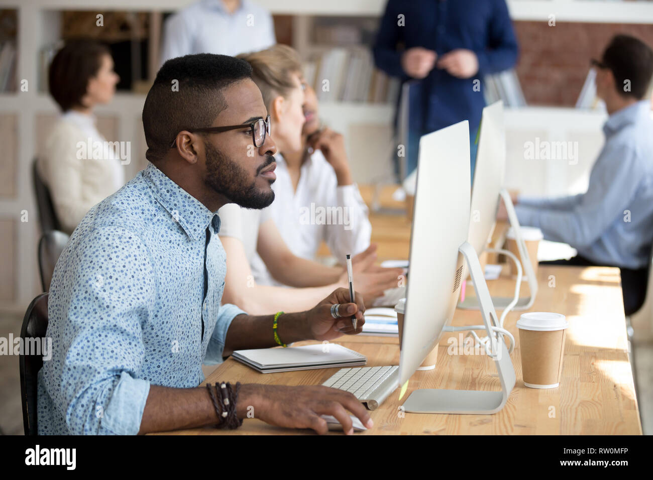 Black manager holding pen make notes on textbook using pc Stock Photo
