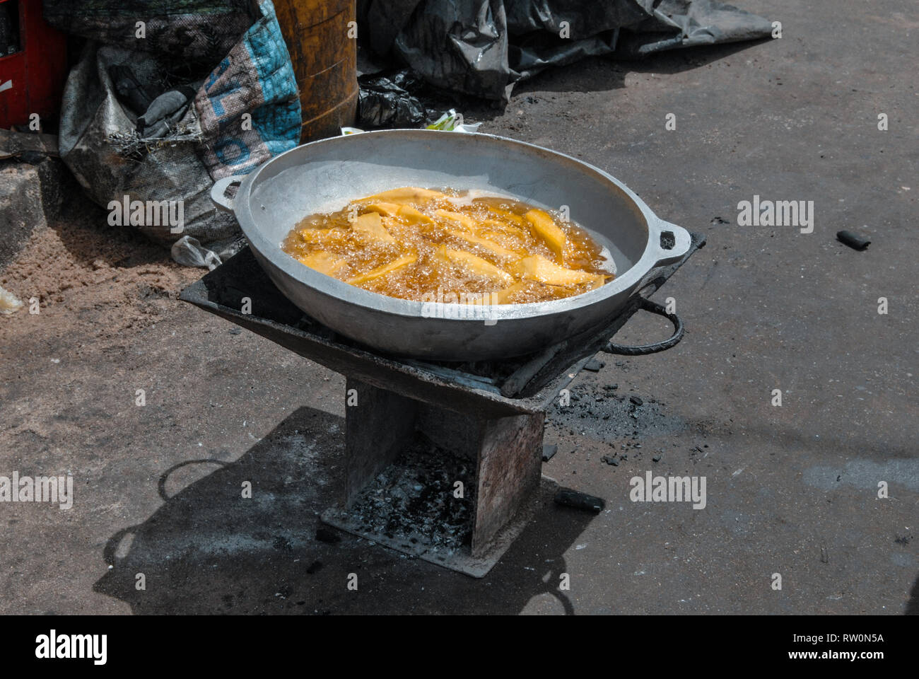 A photo of a oven and plantain balls dumplings boiling in a hot oil on a street of the coastal town of Elmina, Ghana, West Africa Stock Photo