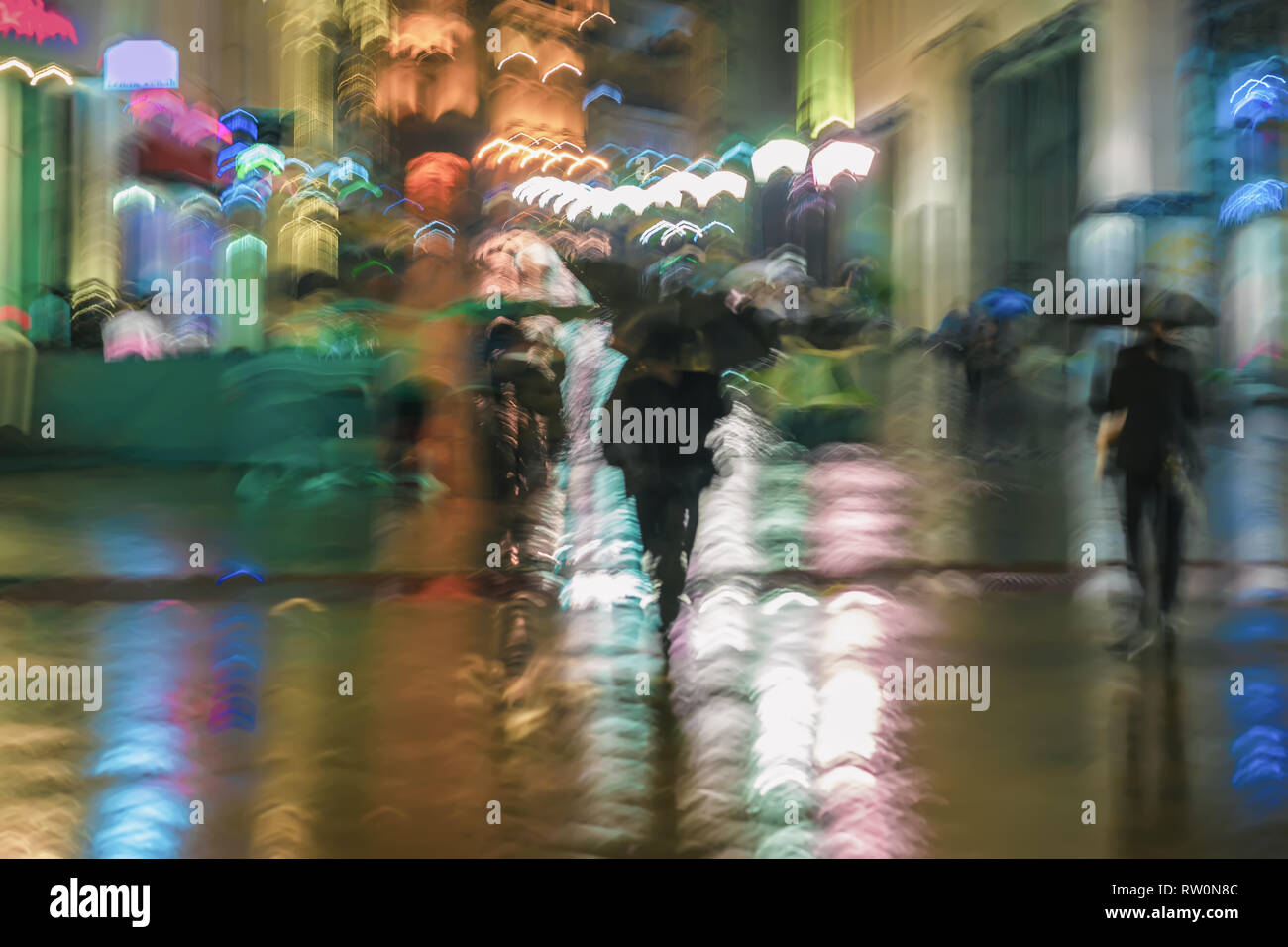 Abstract background of blurred people under umbrellas hurrying down the ...