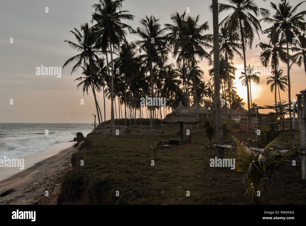 A beautiful sunset at a tropical beach full of palm trees near Elmina, Ghana, West Africa Stock Photo