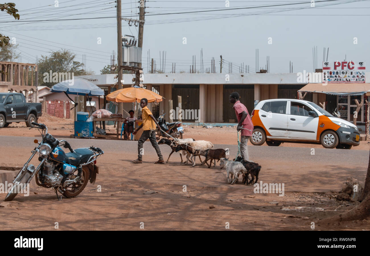 A busy street of a Ghanaian town called Bolgatanga. A man is walking with coats on the street Stock Photo