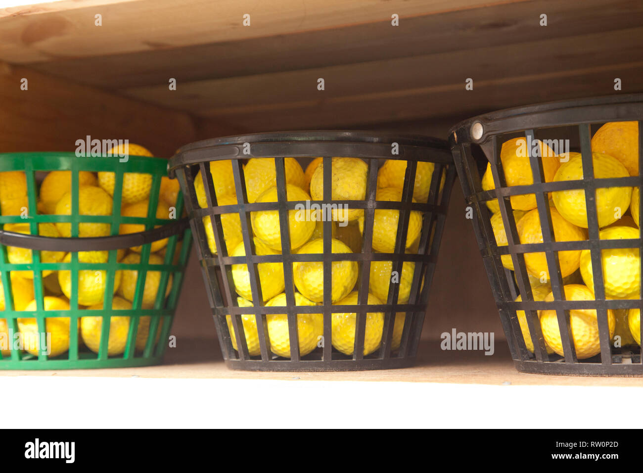 Three plastic buckets filled with yellow balls for the driving range