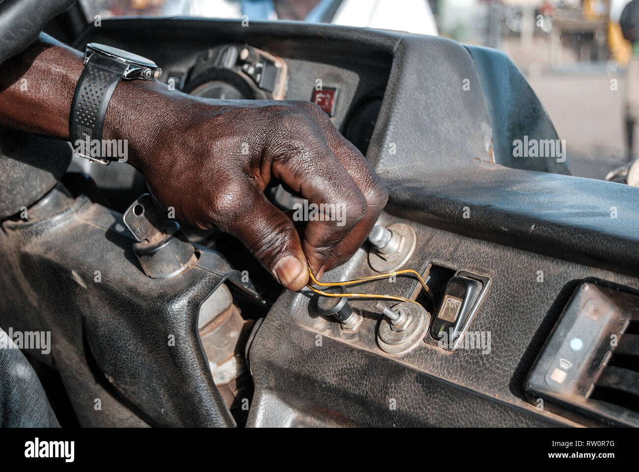 Broken starter. A closeup of a hand of a Ghanaian bus driver who is starting the bus engine by short circuiting two wires. Stock Photo