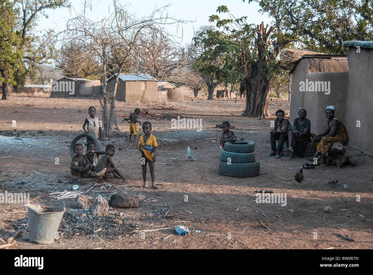 A photo of Ghanaian children posing for the camera as they are playing with old car tyres in the yard. Taken in a savanna of Ghana. Stock Photo