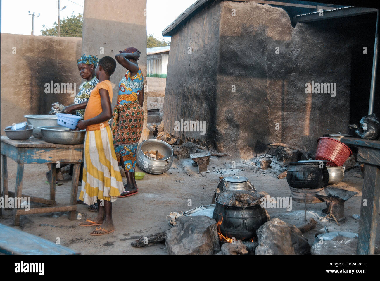 Women of a Ghanaian family are cooking a meal together in a traditional kitchen of a house in rural Ghana Stock Photo