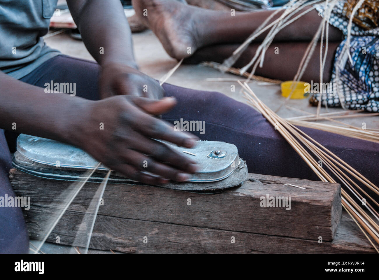 A closeup photo of the hands of a woman weaving the famous Bolga market basket using the straws of the elephant grass (vera veta). Stock Photo