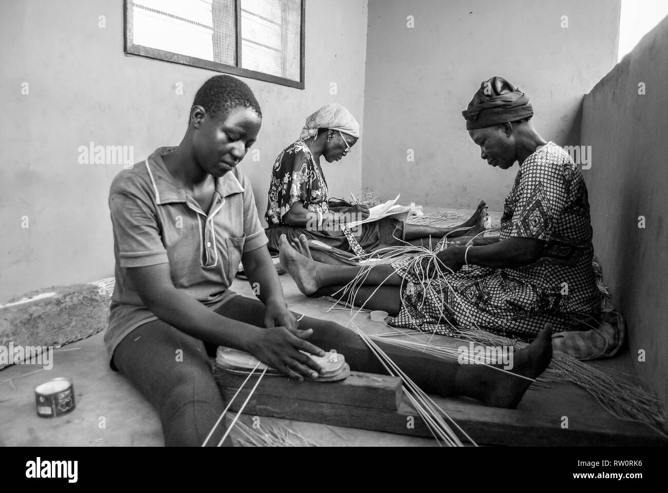 A black and white photo of local Ghanaian women weaving the famous Bolga (Bolgatanga) handwoven market baskets at their home in Kongo village, Ghana. Stock Photo