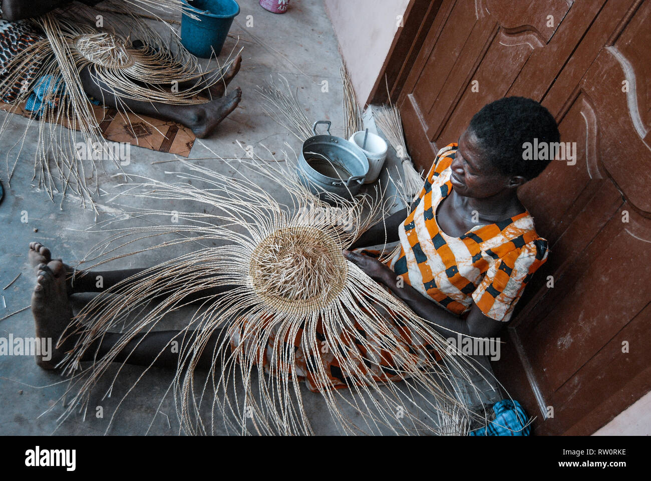 A photo of a local Ghanaian woman weaving the famous decorative and beautiful Bolga market basket. Stock Photo