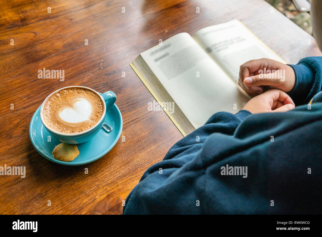 Woman hand reading book and drinking coffee Stock Photo